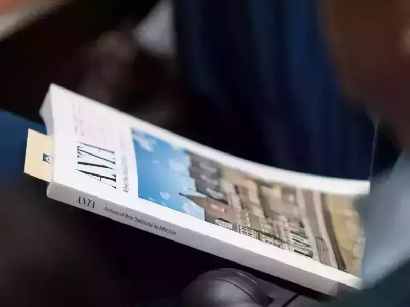 Image of a person holding a white journal with an image of houses on it (ANTA 5) with a book mark inside.